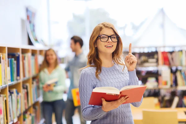 Lycklig student tjej eller kvinna med bok i biblioteket — Stockfoto