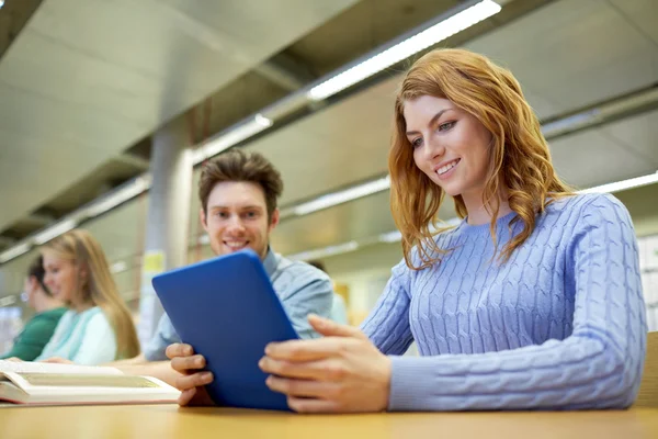 Happy students with tablet pc in library — Stock Photo, Image