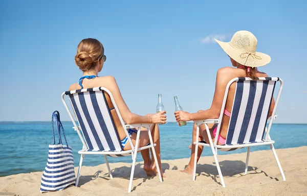 Glada kvinnor i lounger att sola på stranden — Stockfoto