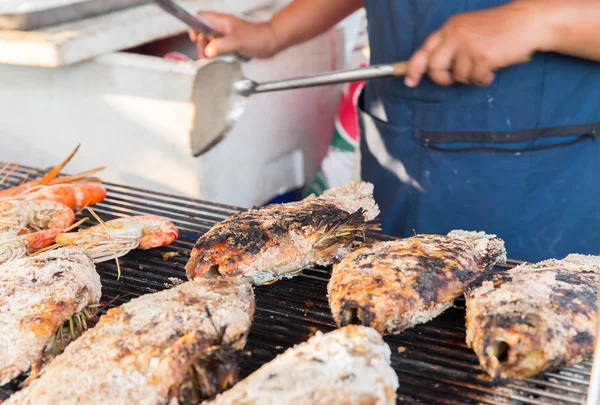 Close up of cook hands grilling fish on street — Stock Photo, Image