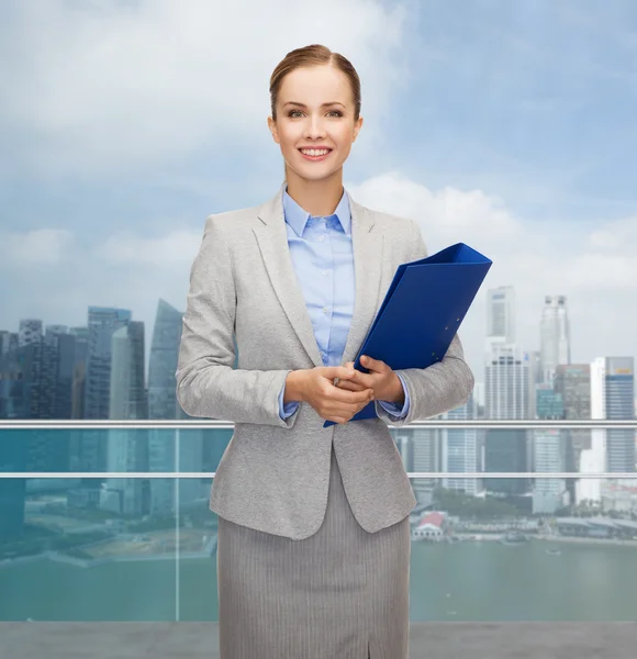 Sonriente mujer de negocios sosteniendo carpeta sobre ciudad — Foto de Stock