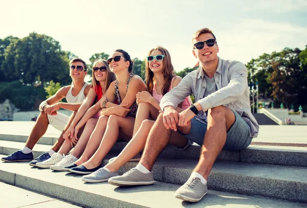 Gruppo di amici sorridenti seduti sulla strada della città — Foto Stock