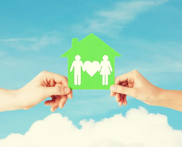 Hands holding green house with family — Stock Photo, Image