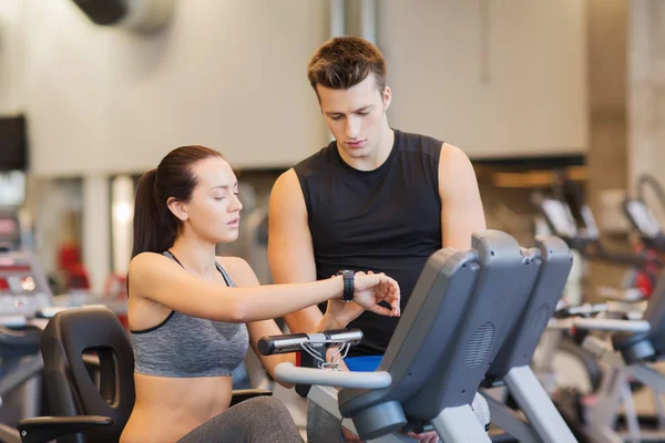 Woman with trainer on exercise bike in gym — Stock Photo, Image