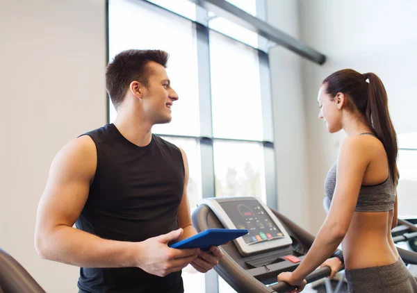 Glad kvinna med tränare på löpband i gym — Stockfoto