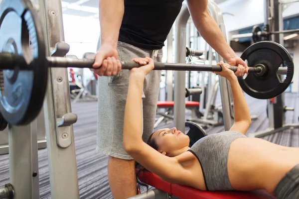 Man en vrouw met lange halter flexing spieren in de sportschool — Stockfoto