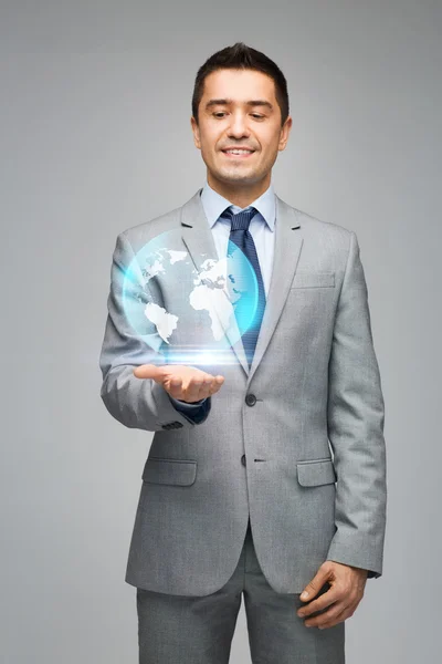 Hombre de negocios feliz en traje mostrando holograma globo —  Fotos de Stock