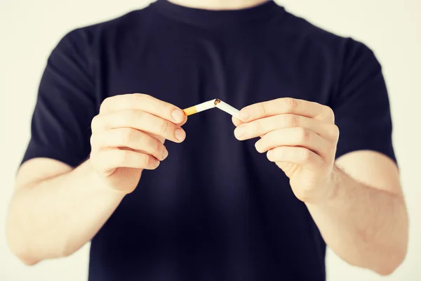 Homem quebrando o cigarro com as mãos — Fotografia de Stock