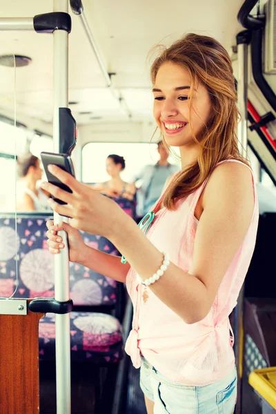 Улыбающаяся девочка-подросток со смартфоном едет на автобусе — стоковое фото
