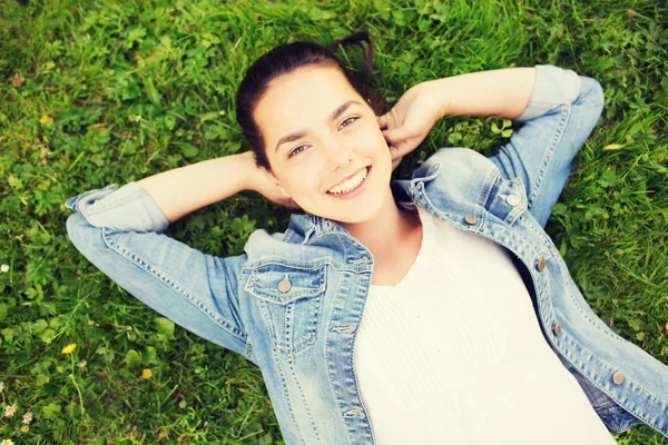 Usměvavá mladá dívka leží na trávě — Stock fotografie