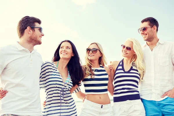 Smiling friends in sunglasses talking on beach — Stock Photo, Image