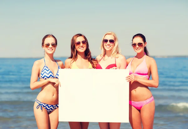 Grupo de mujeres sonrientes con tablero en blanco en la playa — Foto de Stock