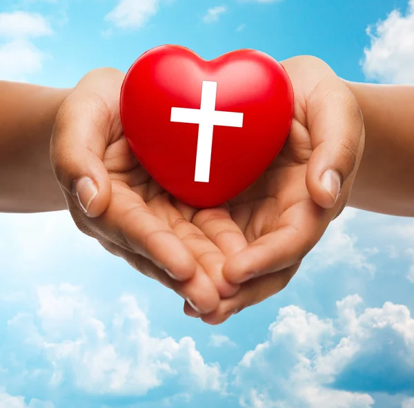 Primer plano de las manos sosteniendo el corazón con símbolo de cruz —  Fotos de Stock