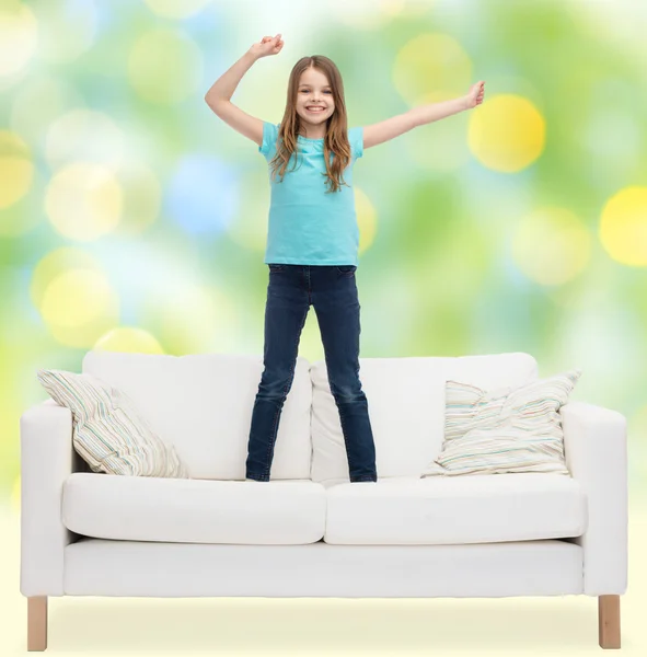 Uśmiechnięta dziewczynka skacze na kanapie — Zdjęcie stockowe