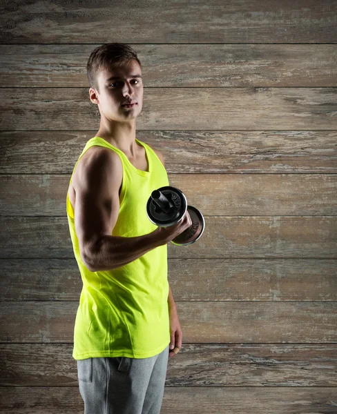 Mladý muž s činka protahuje biceps — Stock fotografie