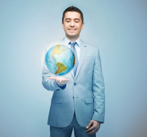 Hombre de negocios feliz en traje mostrando holograma globo — Foto de Stock