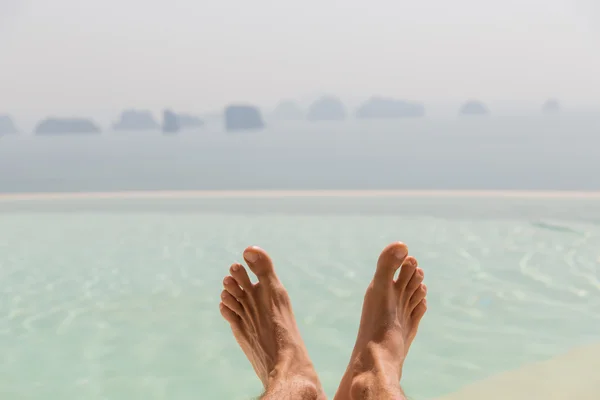Närbild av manliga fötter över hav och himmel på stranden — Stockfoto
