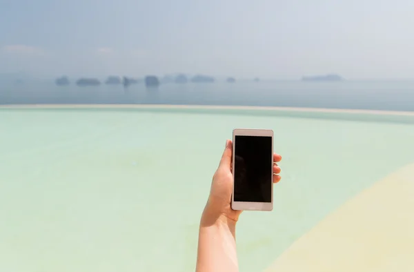 Primer plano de la mano femenina con smartphone en la playa — Foto de Stock