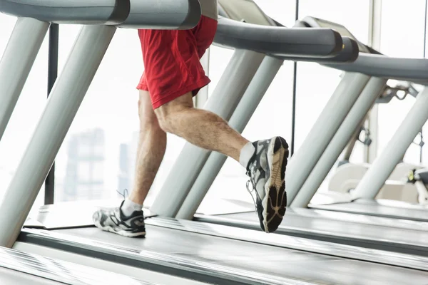 Крупный план мужских ног, бегающих по беговой дорожке в спортзале — стоковое фото