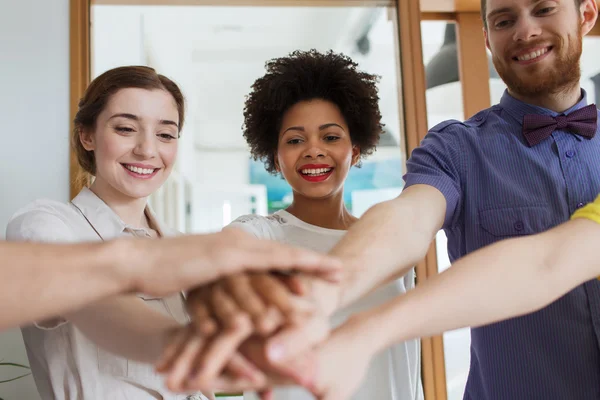 Lyckliga kreativa team ith händer på topp i office — Stockfoto