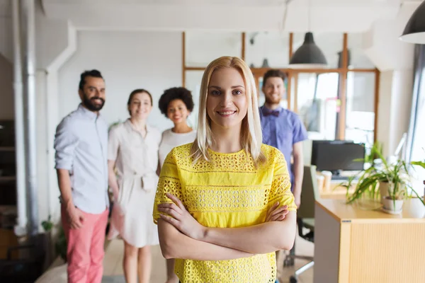 Happy young woman over creative team in office — Stock Photo, Image