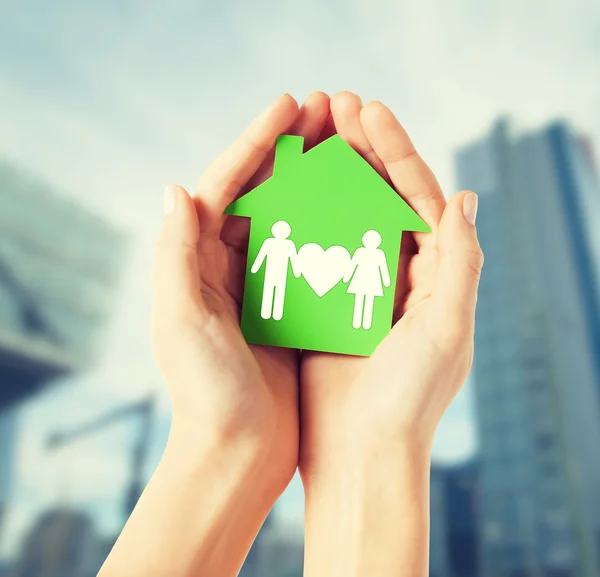 Hands holding green house with family — Stock Photo, Image