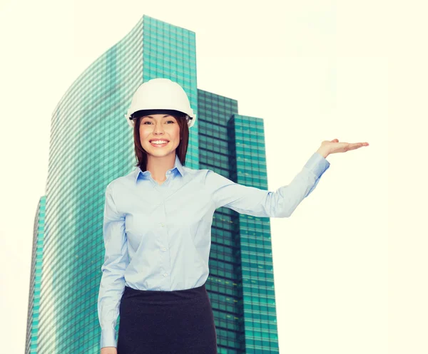 Businesswoman in helmet holding something on palm — Stock Photo, Image