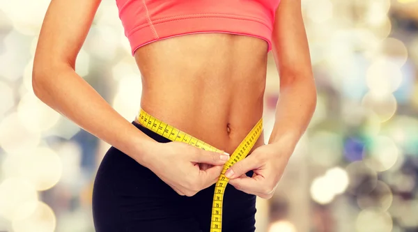 Close up of female hands measuring waist — Stock Photo, Image