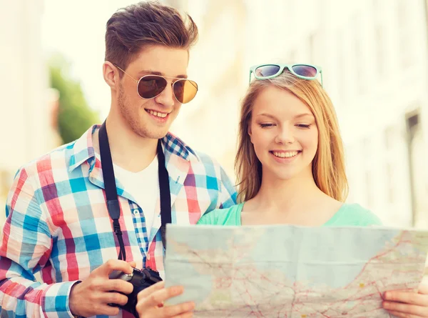 Smiling couple with map and photo camera in city — Stock Photo, Image