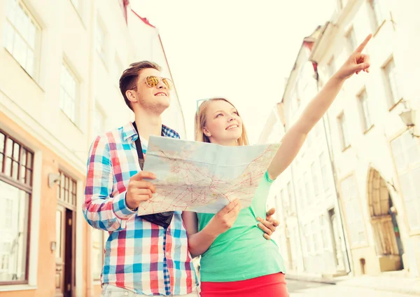 Casal sorridente com mapa e câmera de fotos na cidade — Fotografia de Stock