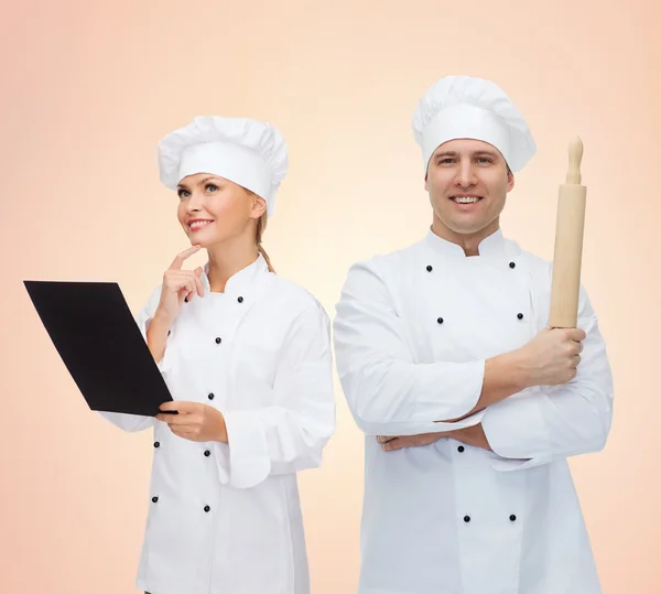 Happy chefs or cooks couple holding rolling pin — Stock Photo, Image