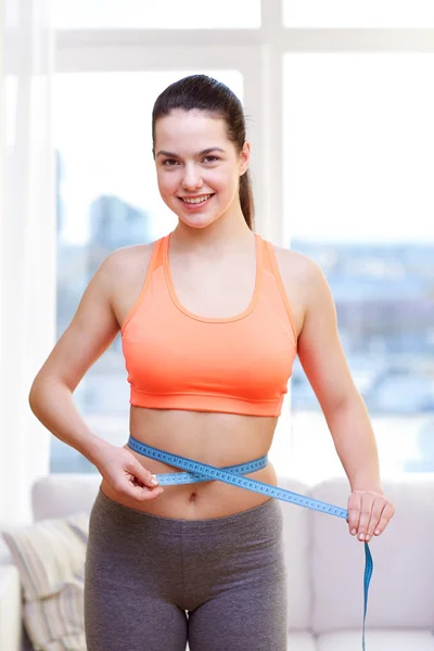 Mulher desportiva feliz medindo sua cintura com fita — Fotografia de Stock