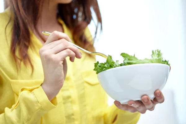 Primer plano de la mujer joven comiendo ensalada en casa — Foto de Stock