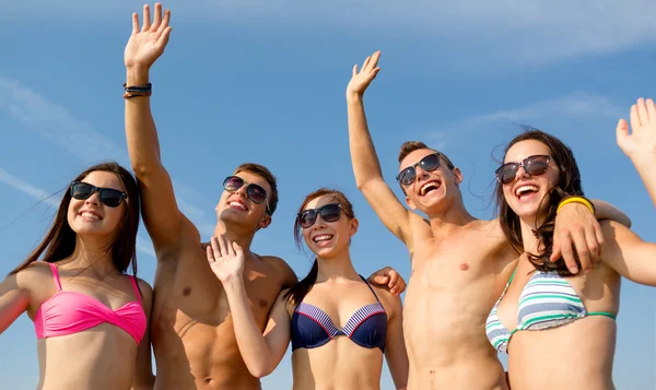 Улыбающиеся друзья в солнечных очках на летнем пляже — стоковое фото