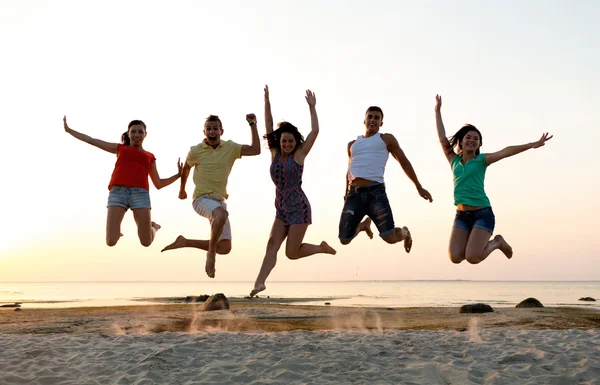 Amigos sonrientes bailando y saltando en la playa —  Fotos de Stock