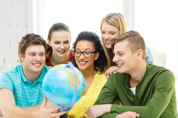 Пять улыбающихся студентов смотрят на глобус в школе — стоковое фото