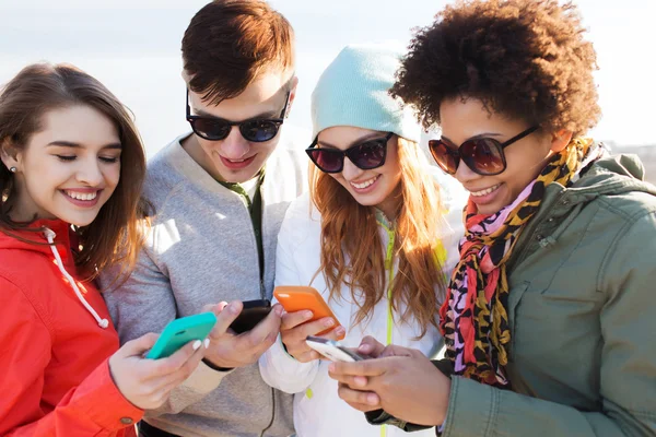 Amigos sonrientes con teléfonos inteligentes — Foto de Stock