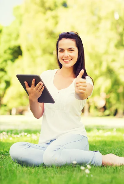 微笑年轻的女孩坐在草地上的 tablet pc — 图库照片