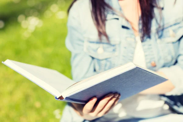 Close up of young girl with book in park — Stock Photo, Image