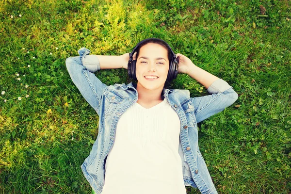 Sorridente ragazza in cuffia sdraiata sull'erba — Foto Stock