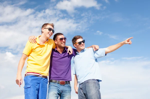 Smiling friends in sunglasses pointing finger — Stock Photo, Image