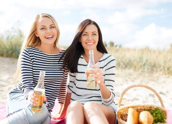 Щасливі молоді жінки п'ють пиво на пляжі Стокове Фото
