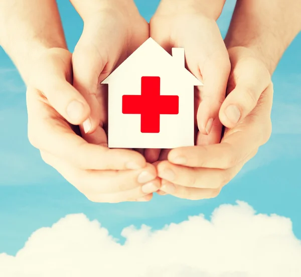 Hands holding paper house with red cross — Stock Photo, Image