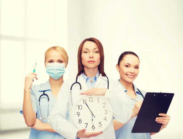 Calm female doctor and nurses with wall clock — Stock Photo, Image