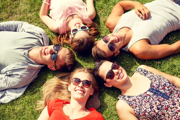 Groupe d'amis souriants couchés sur l'herbe à l'extérieur — Photo