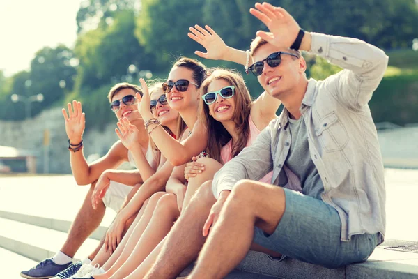 Gruppo di amici sorridenti seduti sulla strada della città — Foto Stock