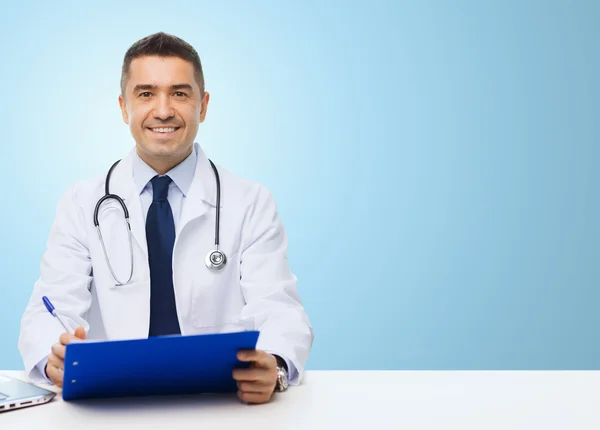 Médico feliz com área de transferência sobre fundo azul — Fotografia de Stock