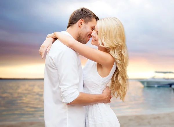 Feliz pareja abrazándose al atardecer en la playa de verano — Foto de Stock