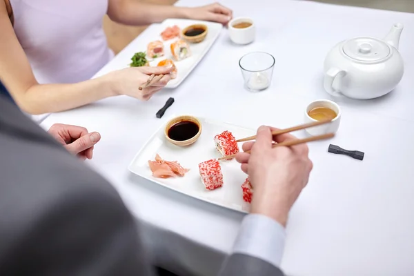 Close up of couple eating sushi at restaurant — Stock Photo, Image