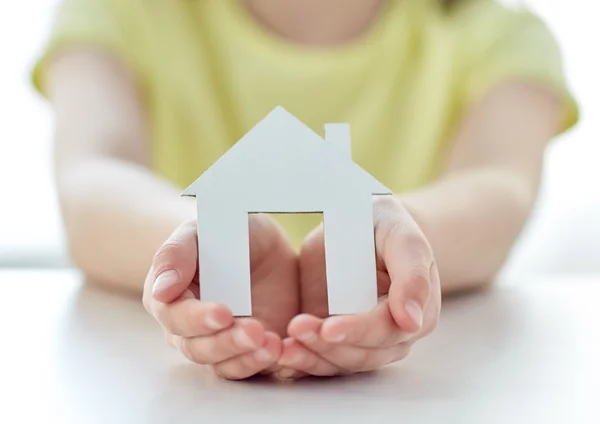 Nahaufnahme glücklicher Mädchenhände mit Papierhaus — Stockfoto